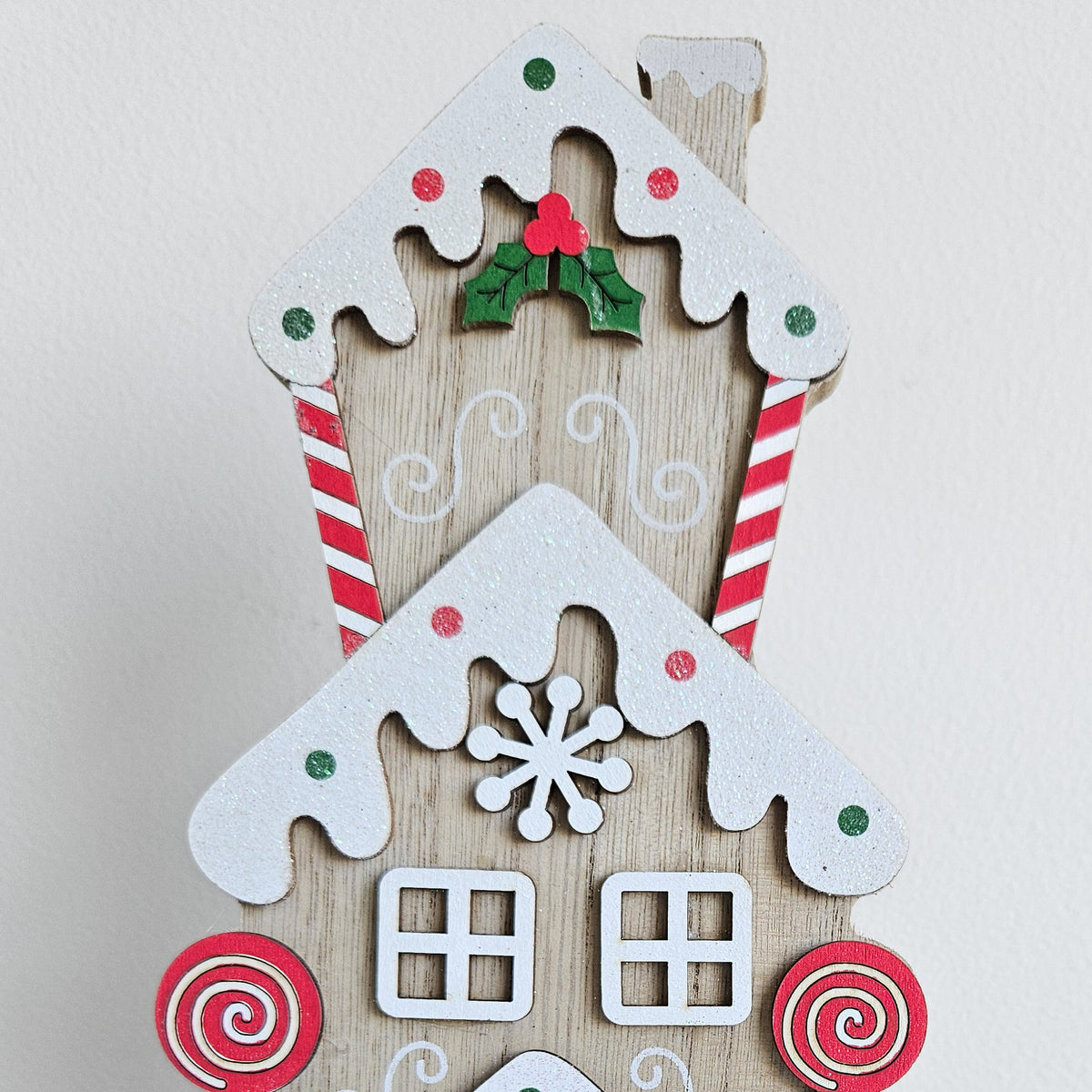 Close-up of the gingerbread townhouse with snowy roof, holly, snowflake and candy cane details