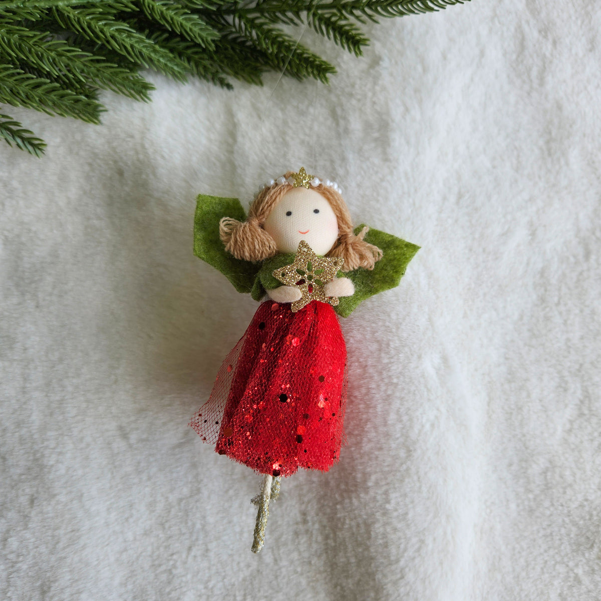 Christmas angel ornament with a red glittery tulle skirt, green felt wings, pigtails and a gold star