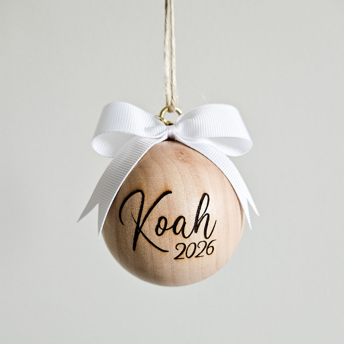 6cm personalised wooden bauble with white bow and engraved name Koah with year 2026