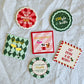 Set of six colourful Christmas Cocktail ceramic coasters with festive sayings in red, green, pink and cream