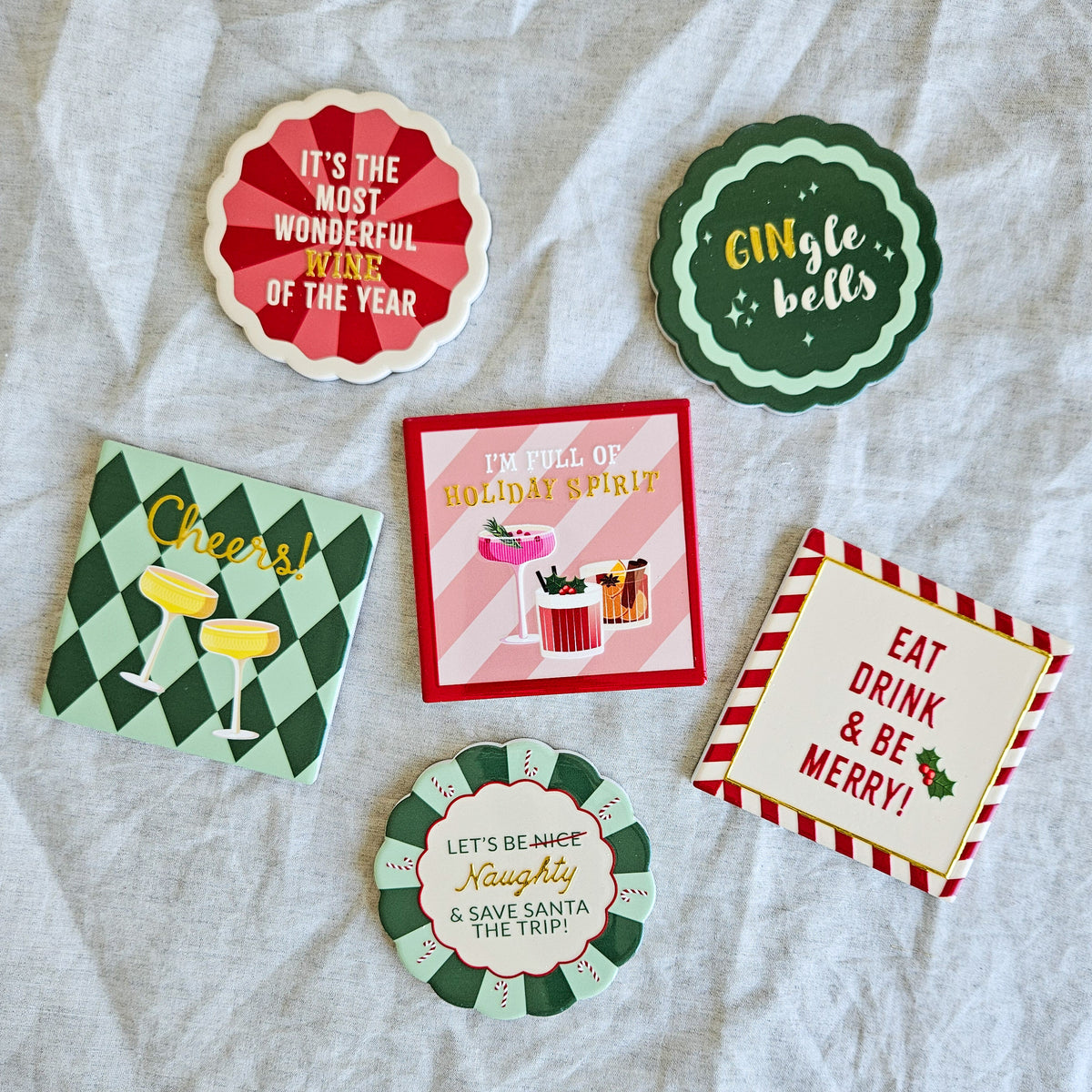 Set of six colourful Christmas Cocktail ceramic coasters with festive sayings in red, green, pink and cream