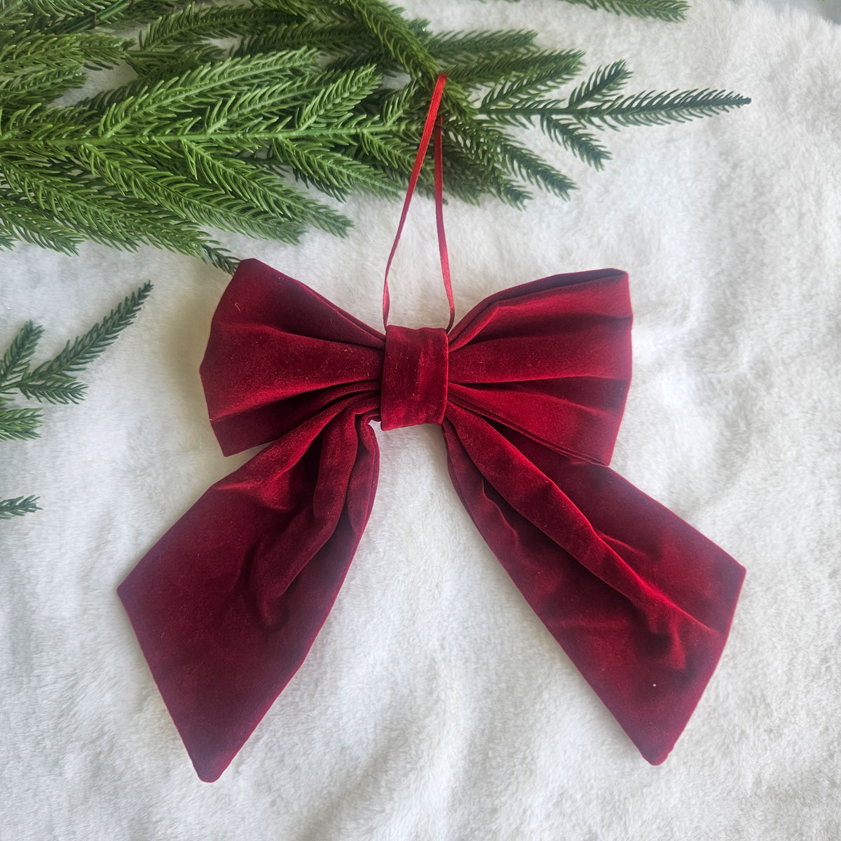 Deep red velvet-style Christmas bow ornament with a matching hanging ribbon