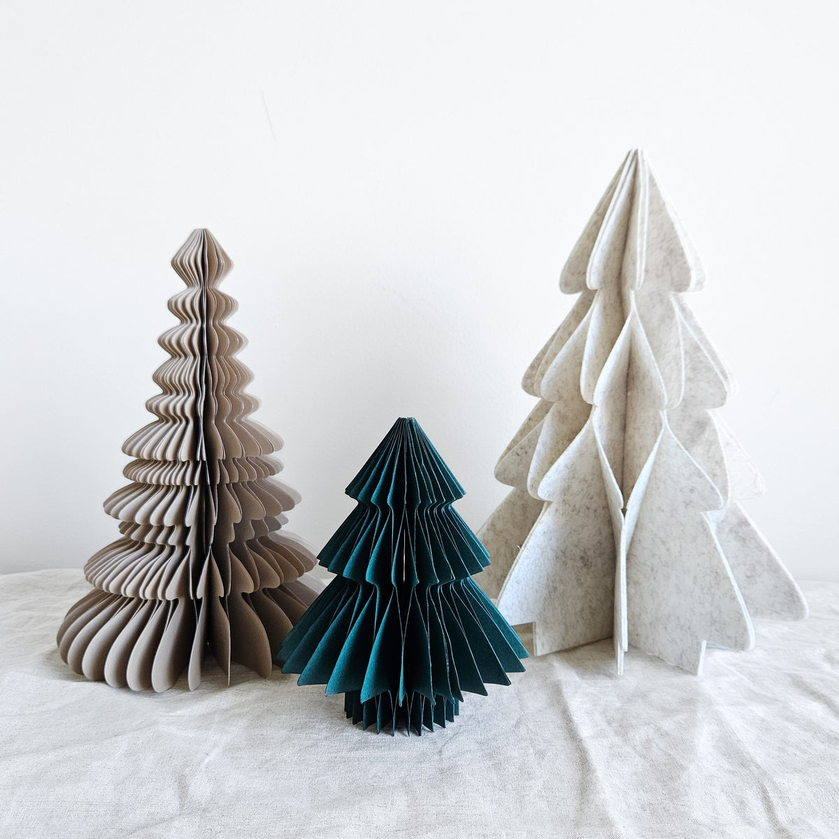 Three tabletop Christmas trees: natural tiered paper, deep green paper and soft ivory felt